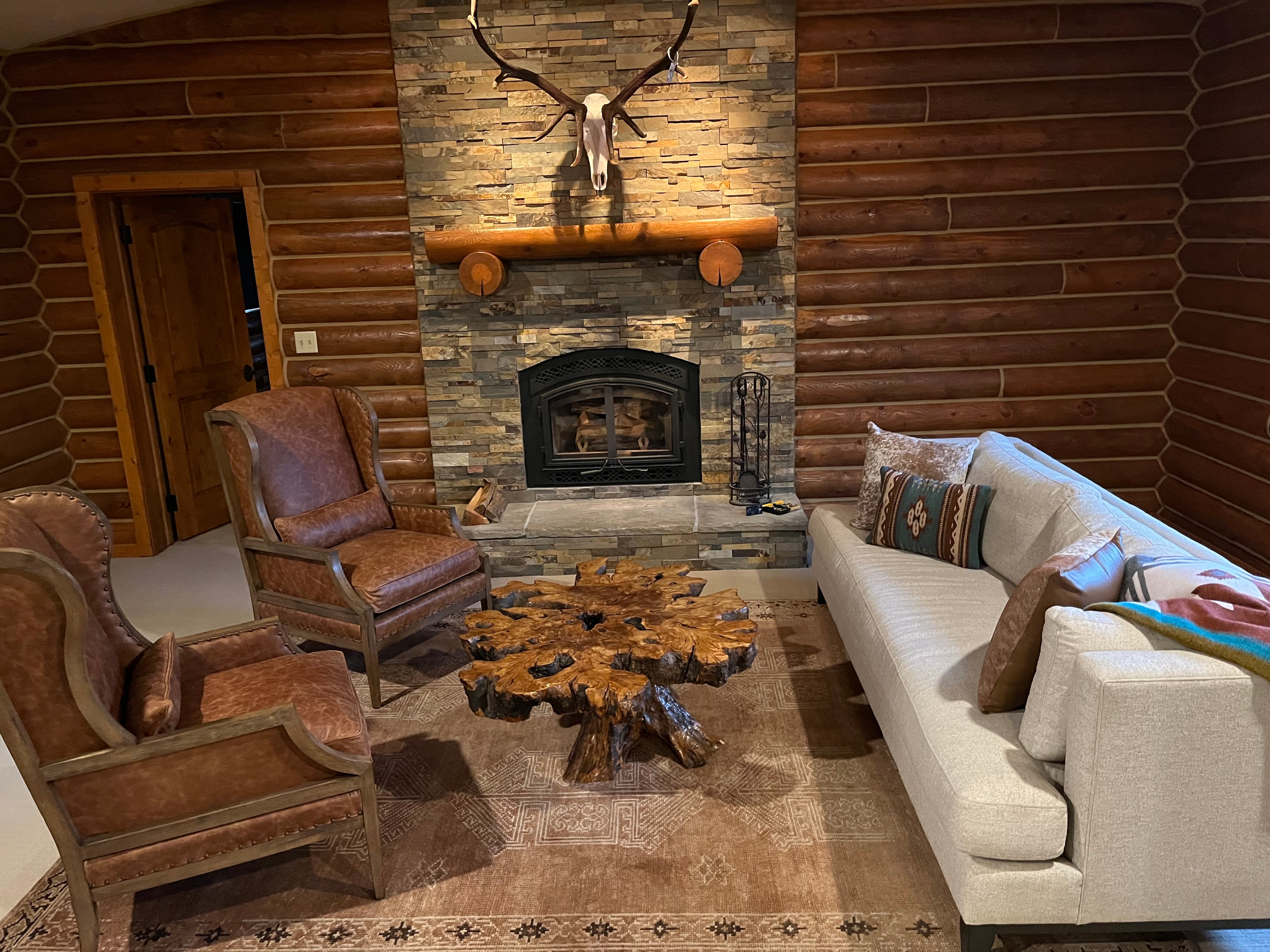 Cozy living room with wooden walls, fireplace, and furniture with a rug from our Bellevue Rugs Collection.